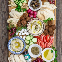 a morroccan inspired charcuterie board with houmous, pita bread, olives, tomato,cucumber,falafels, feta cheese and more delicacies