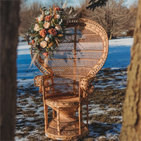 a rattan peackock chair decorated with pink flowers in snowy nature