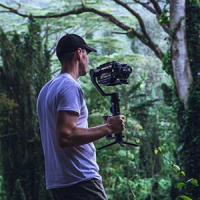 Man carrying a video camera attached on a gimbal in nature