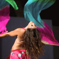 A greek bellydancer wearing a pink costuming and dancing with fanveils during an arabic inspired event in Helsinki Finland